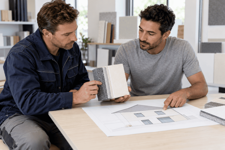 Artisan et conseiller examinant un échantillon d’isolation et un plan de façade